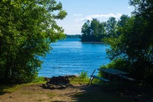 A Loon Swimming On The St. Lawrence River Next To A Campsite With A Fire Pit, Picnic Table And Waterfront At Milles Roches Campground Located In Long Sault Ontario Canada