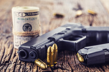 Gun And Money. 9 Mm Pistol Gun Bullets Strewn And Roll Dollar Banknotes On Rustic Oak Table