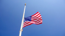 American Flag At Half Mast Aka Half Staff Against Clear Blue Sky
