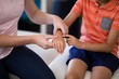 © WavebreakMediaMicro - Midsection of female therapist examining hand with boy sitting