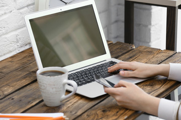 Wall Mural - Young woman with laptop and phone at table