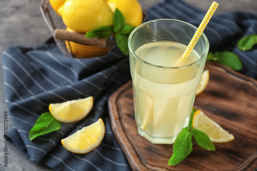 Composition with glass of lemon juice and fresh lemons on table