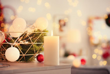 Burning Candle And Christmas Decorations On Table Indoors
