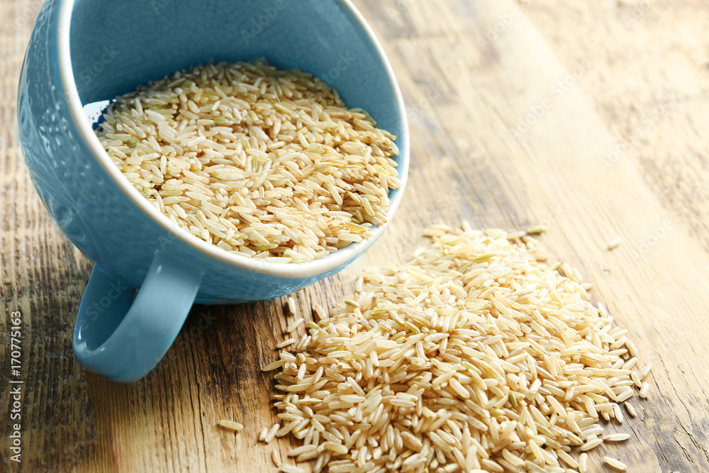 Cup of long grain brown rice on table