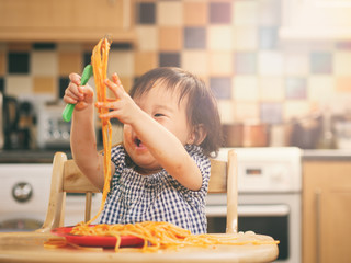 Wall Mural - baby girl eating messy spaghetti at home