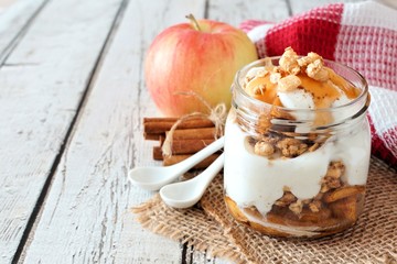 Wall Mural - sweet baked apple parfait in a mason jar on a rustic white wood background