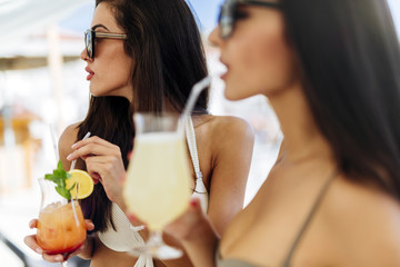 Wall Mural - Beautiful women on beach enjoying cocktails