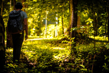 man traveling walking with backpack at national park in the jungle day time sun shine on holiday at weekend relax fresh on background nature view