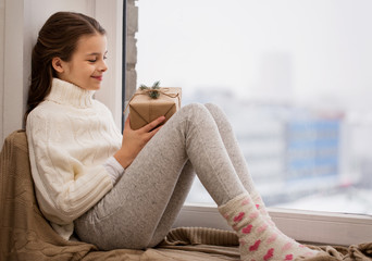 Poster - girl with christmas gift sitting on sill at home