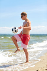 Wall Mural - young man with ball playing soccer on beach