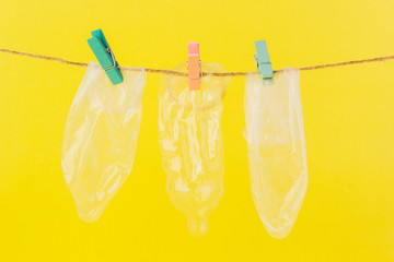 Wall Mural - Condoms hanging on a rope against a yellow background.