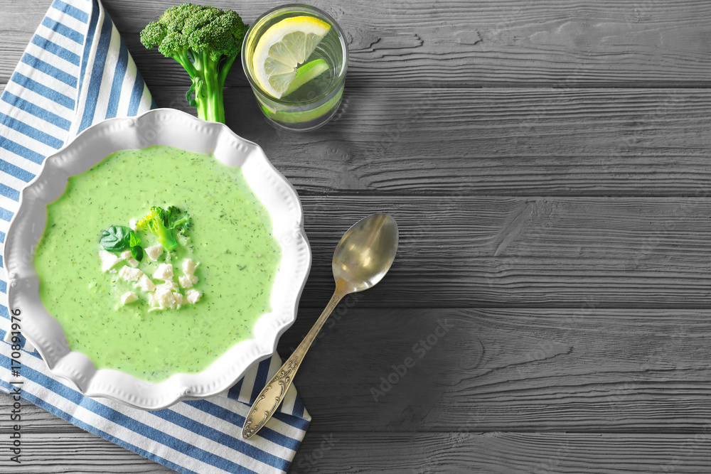 Plate with delicious broccoli soup on wooden background