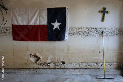 A Texas Flag And A Cross Hang On The Wall Of A Flooded And Now