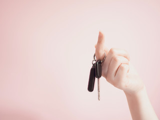 asian woman hanging car key by beauty finger with pink pastel background