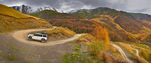 Mountain Serpentine In The Autumn Mountains, Bright Autumn Colors, In The Background The Peaks Covered With Snow