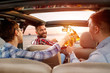 © luckybusiness - Friends enjoying a road trip in the car.