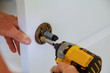 © ungvar - Installation of door lock using a screwdriver to. Carpenter at lock installation with electric drill into wood door.