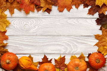 Wall Mural - Autumn leaves and pumpkins over old wooden background