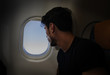 © theartofphoto - Side view of handsome young man against plane window sitting and looking out