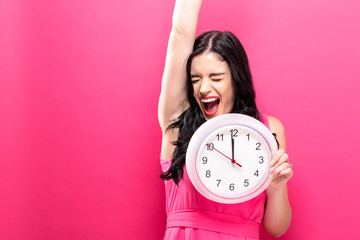 Wall Mural - Young woman holding a clock showing nearly 12
