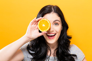 Canvas Print - Happy young woman holding oranges on a yellow background