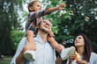 © katie_martynova - Happy young family playing with bubble wands in park outdoors