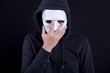 Mystery man holding and wearing white mask for hide his face. Anonymous social masking or halloween concept.