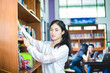 © tuiphotoengineer - Asian female students holding for selection Book  in library