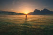 Girl standing on golden field towards the rising sun