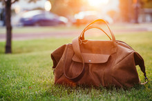 Retro Brown Shoes And Man Leather Bag In Bright Colorful Summer Grass In The Park