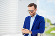 © baranq - Cheerful handsome business executive using phone to work while outside in urban setting