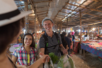 Wall Mural - tourists on tropical street market in thailand young people buying fresh fruits and vegetables on as