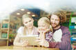 © pressmaster - Young parents and little daughter watching curious video in tablet at leisure