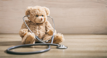 Wall Mural - Teddy bear and a stethoscope on a wooden floor