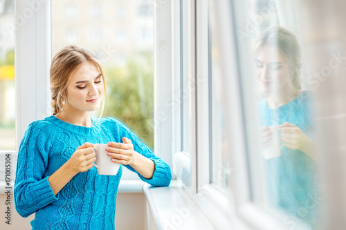 Fotografía Young girl drinks coffee with milk and reflects