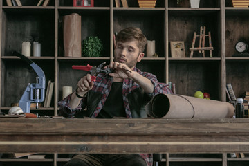 Young man leather manufacturer holding hole punch and select diameter