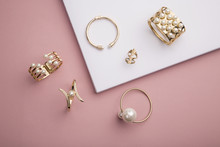 Pearl Golden Bracelets And Ring On Pink And White Background