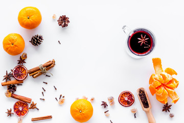 Hot mulled wine or grog cooking for new year celebration with oranges and spices ingredients on white background flat lay mock up