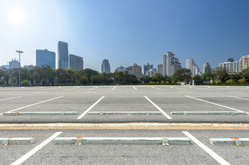 Wall Mural - Empty parking lot at city center with blue sky and sun reflection