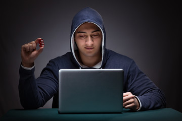 Wall Mural - Young man wearing a hoodie sitting in front of a laptop computer