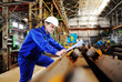 © Evgeniy Kalinovskiy - Engineer-builder working with documents on the construction site. Worker inspects drawings on the construction site against the background of factory equipment