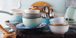 Ceramic and enamel crockery tableware on wooden background. Pastel vintage colors