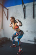 © alfa27 - muscular woman doing lunges with a sand bag.