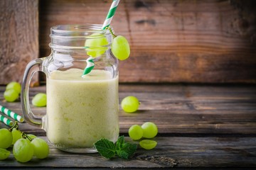 Wall Mural - green organic detox grape smoothie in glass mason jar on  wooden background