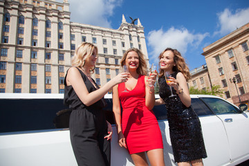 Wall Mural - Beautiful women near a limousine drink champagne.