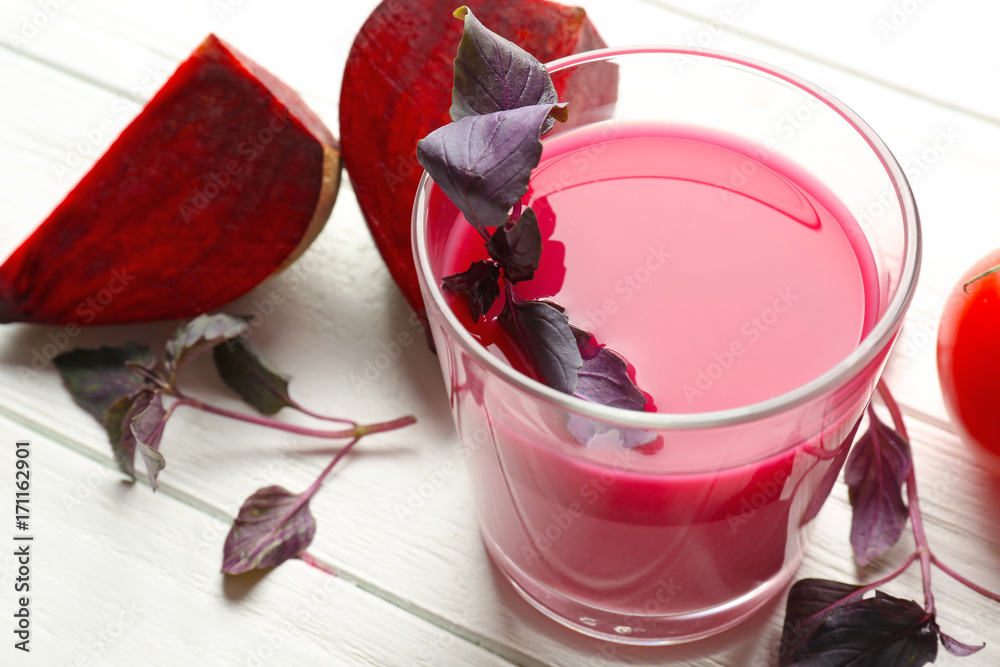 Glass with fresh vegetable juice and ingredients on wooden table