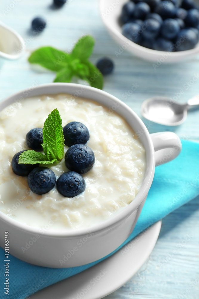 Creamy rice pudding with blueberries on wooden table