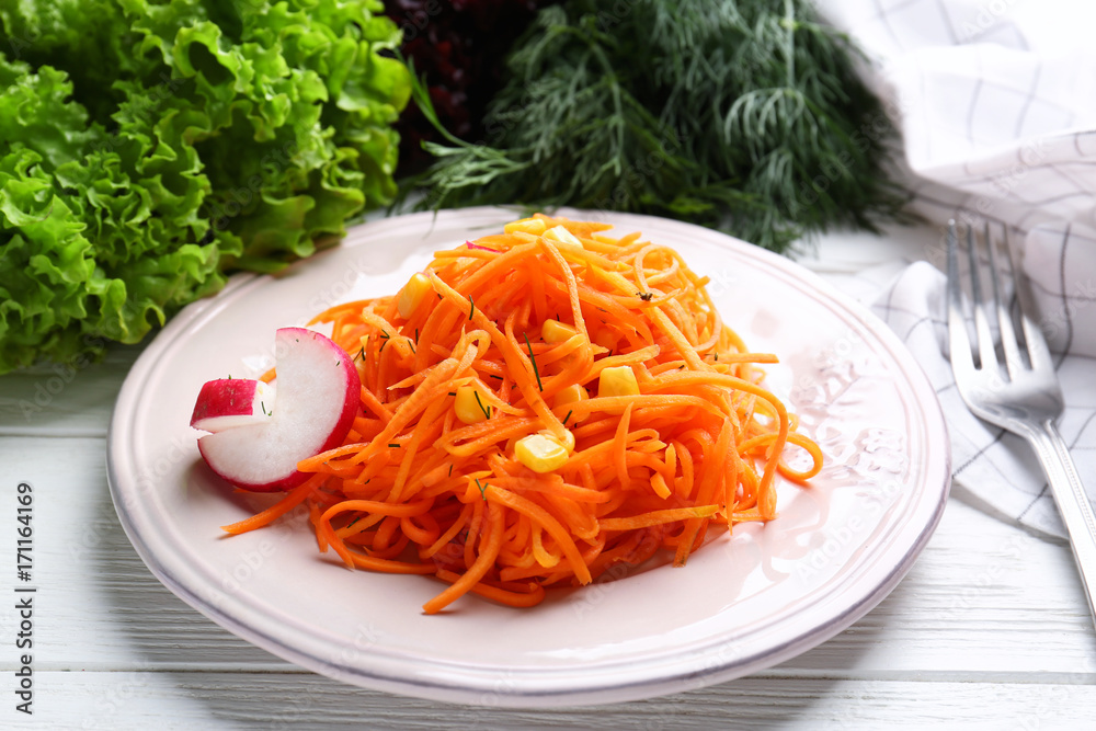 Plate with delicious carrot salad on wooden table