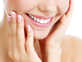 Closeup shot of beautiful female smile and manicured fingers, white background.