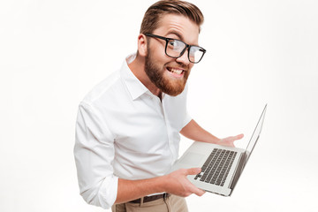 Wall Mural - Funny man in eyeglasses holding laptop and staring at camera